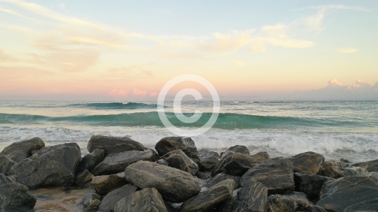 Waves Crashing Over Rocks on Sandy Beach
